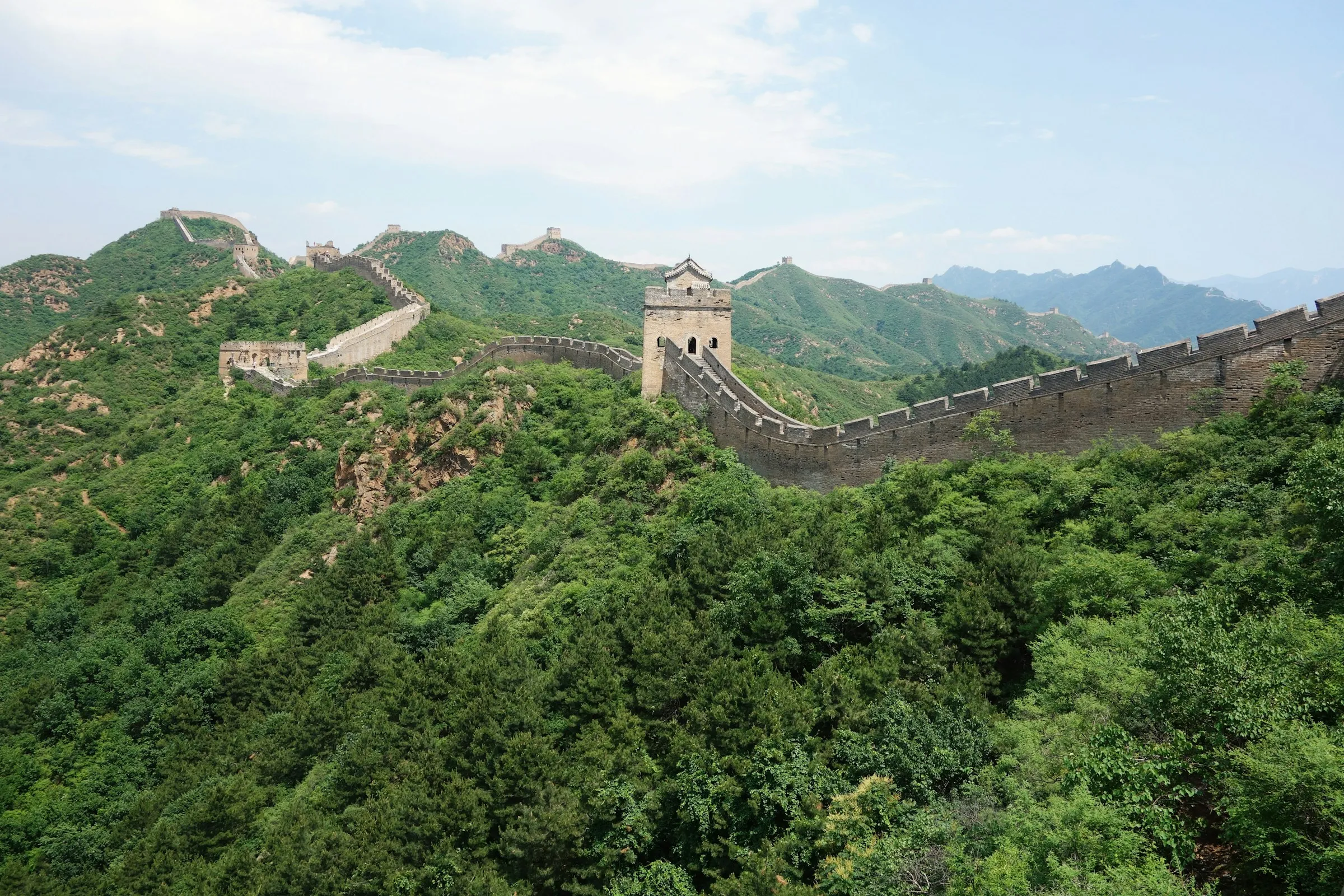 Watchtowers receding into haze along a green ridge at Jinshanling