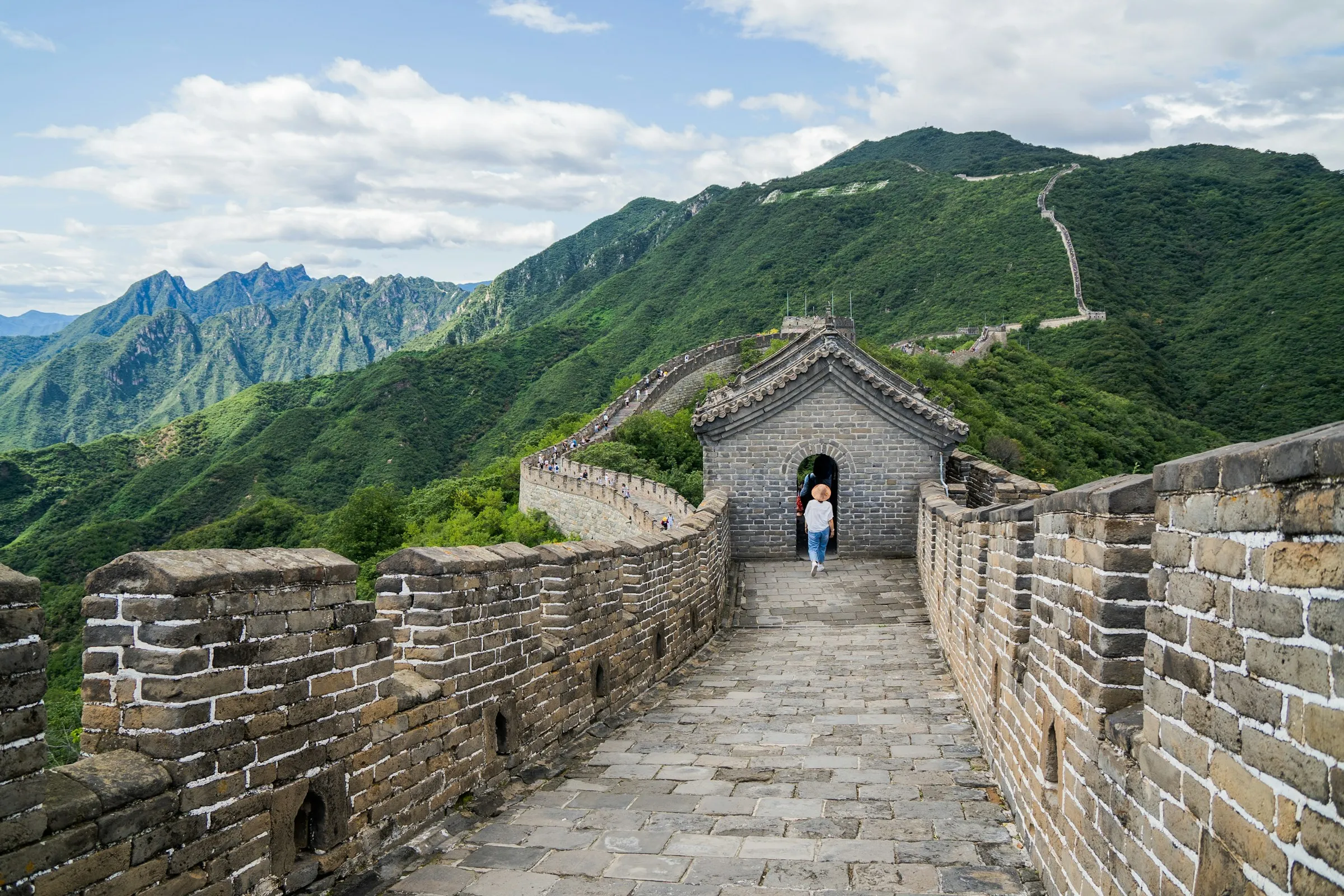 Restored wall at Mutianyu with crenellated parapets on both sides and a tiled-roof gate tower